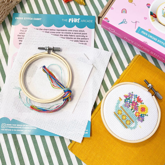 contents of a mini cross stitch kit with a watering can design